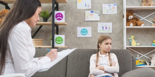 depressed-girl-sitting-sofa-with-female-psychologist-writing-note-clipboard